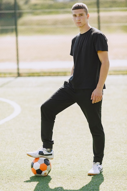 L'uomo gioca a socerl al parco. Torneo su mini-footbal. Ragazzo in tuta sportiva nera.