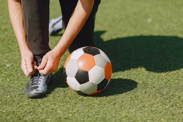 L'uomo gioca a socerl al parco. Torneo su mini-footbal. Ragazzo in tuta sportiva nera.