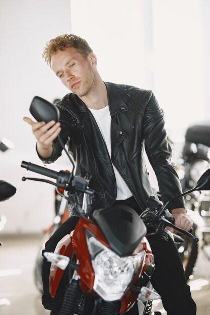 L'uomo ha scelto le motociclette nel negozio di moto. Ragazzo con una giacca nera.