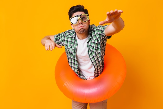 L'uomo in camicia verde, maschera da sub e cerchio gonfiabile rappresenta il nuoto nello spazio arancione.