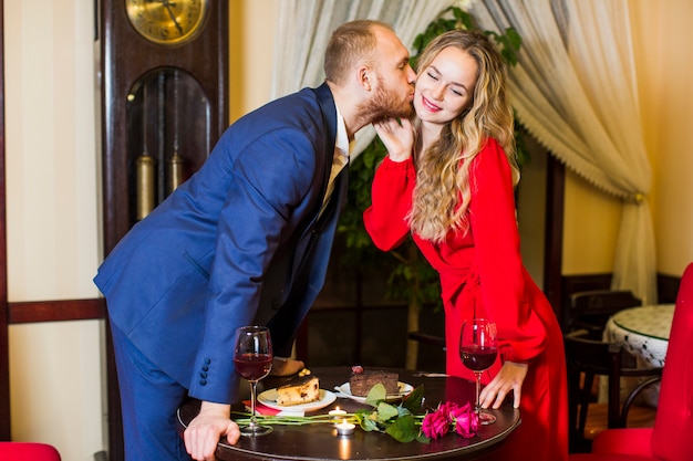 L&#39;uomo in tuta che bacia la donna sulla guancia sopra il tavolo