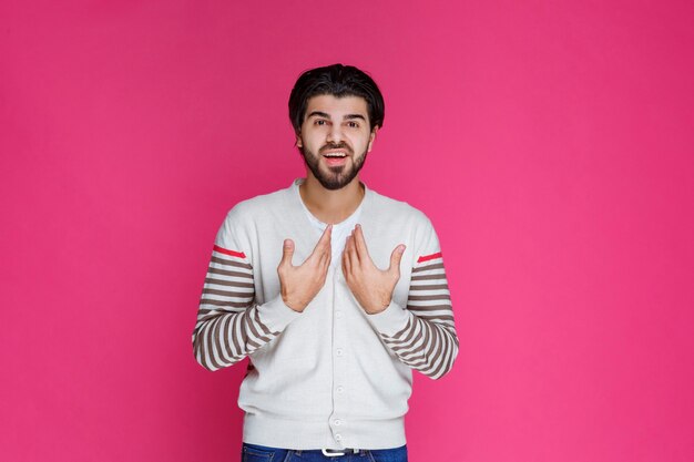 L'uomo in una camicia bianca che indica se stesso e sembra sorpreso.