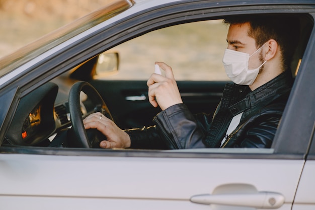 L'uomo in una maschera disinfetta la macchina