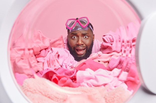 l'uomo indossa la maschera da snorkeling per le immersioni mette il bucato rosa per il lavaggio nelle pose della lavatrice washer