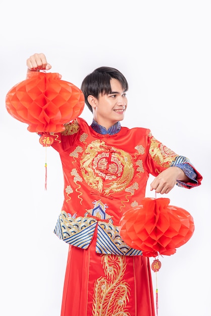 L'uomo indossa lo spettacolo di abiti Cheongsam decora la lampada rossa nel suo negozio nel capodanno cinese