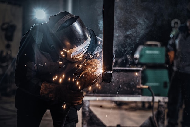 L'uomo lavora in una fabbrica di metalli, sta saldando un pezzo di rotaia usando strumenti speciali.