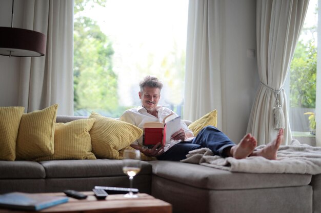 l'uomo legge un libro sul divano di casa