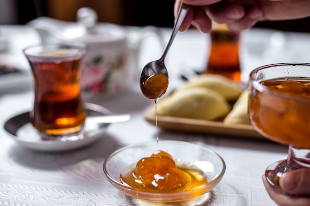 L'uomo mette la marmellata di ciliegia bianca nel piattino dalla vista laterale di vetro diss