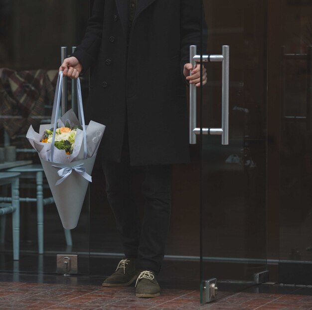 L'uomo nero vestito entrando con un mazzo bianco di fiori