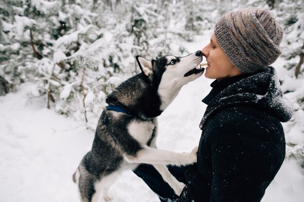 L&#39;uomo nutre i suoi biscotti per cani Husky di bocca in bocca all&#39;aperto in inverno con tempo nevoso