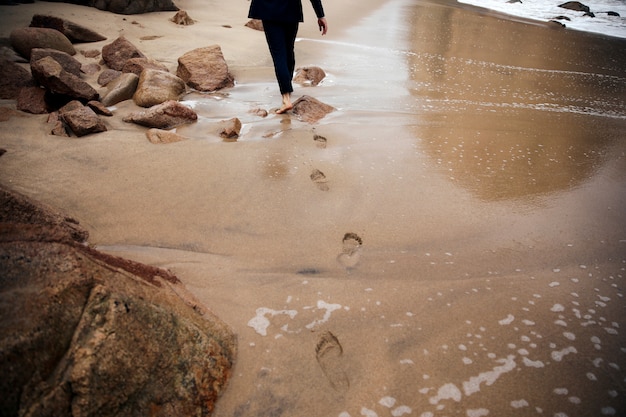 L'uomo scalzo sta camminando attraverso la spiaggia lasciando tracce dietro