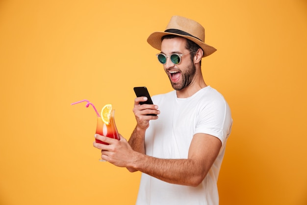 L'uomo sorridente con il cocktail fa la foto per telefono