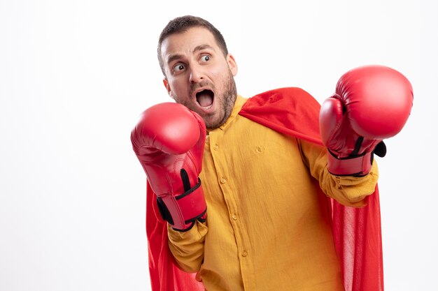 L'uomo spaventato del supereroe sta con i guantoni da boxe isolati sulla parete bianca