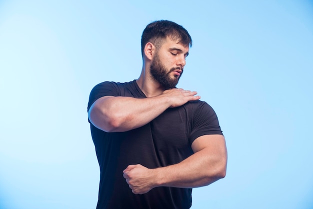 L'uomo sportivo in camicia nera mostra i suoi muscoli