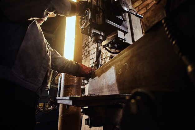 L'uomo sta lavorando con un trapano gigante in una trafficata fabbrica di metalli.