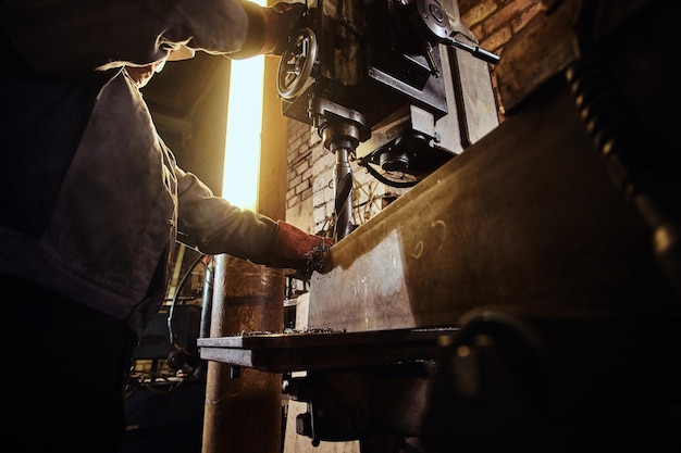 L'uomo sta lavorando con un trapano gigante in una trafficata fabbrica di metalli.