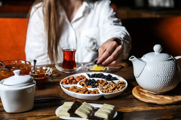L'uomo sta prendendo l'uva passa dalla vista laterale dell'inceppamento matto della frutta secca del cioccolato dell'insieme di tè