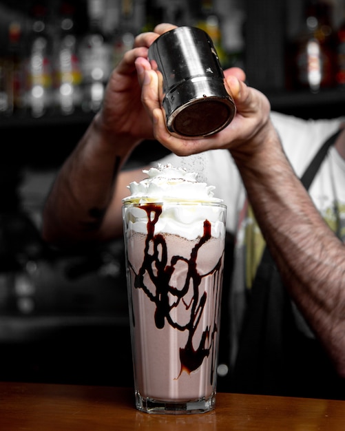 L'uomo sta versando la cannella sulla vista laterale del caffè ghiacciato