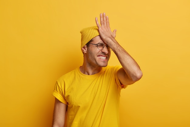 L'uomo stressato e sconvolto tiene il palmo della mano sulla fronte, ha una cattiva memoria, socchiude gli occhi e stringe i denti, indossa abiti casual, non riesce a ricordare cose importanti