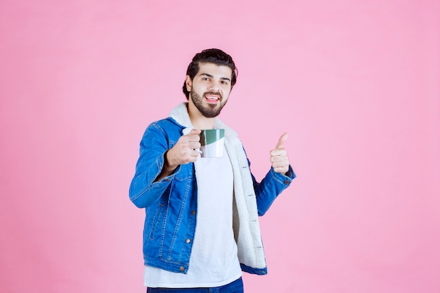 L'uomo tiene in mano una tazza di caffè e ne gode il gusto