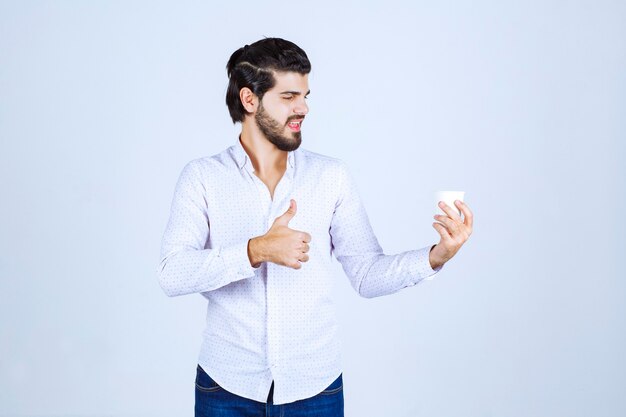 L'uomo tiene in mano una tazza di caffè e ne gode il gusto