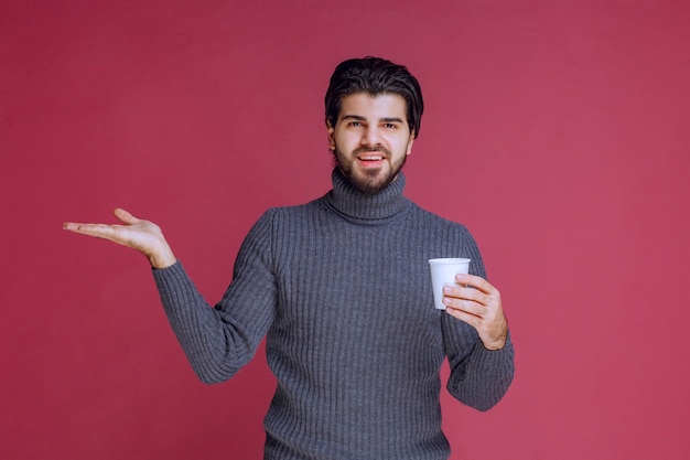 L'uomo tiene in mano una tazza di caffè usa e getta e si sente positivo.