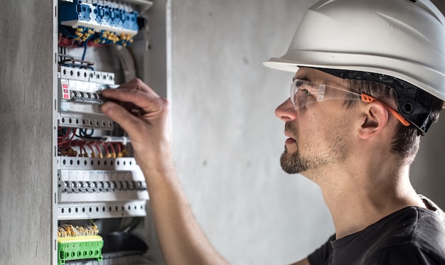 L'uomo, un tecnico elettrico che lavora in un centralino con micce. Installazione e collegamento di apparecchiature elettriche.