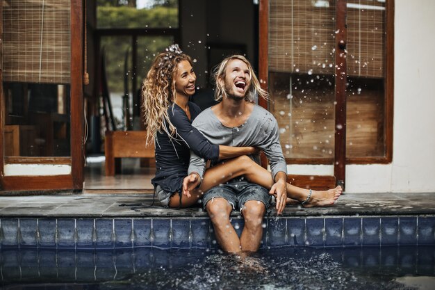 L'uomo vivace e la sua ragazza si abbracciano, ridono e spruzzano acqua