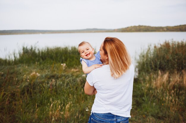 La bambina affascinante osserva sopra la spalla della madre che si leva in piedi prima del lago