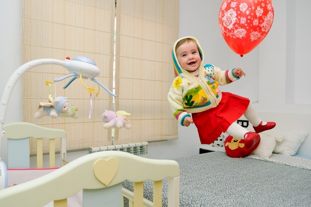 La bambina che salta sul letto con un palloncino