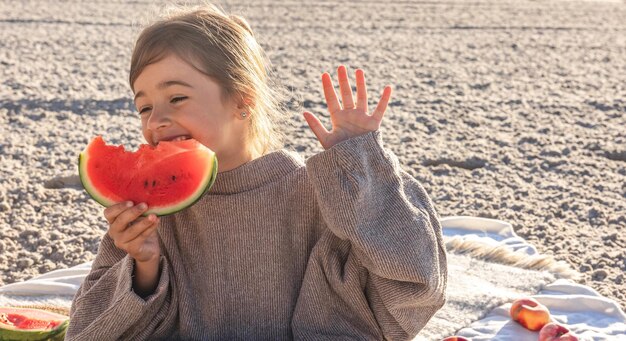 La bambina del primo piano mangia l'anguria sulla spiaggia