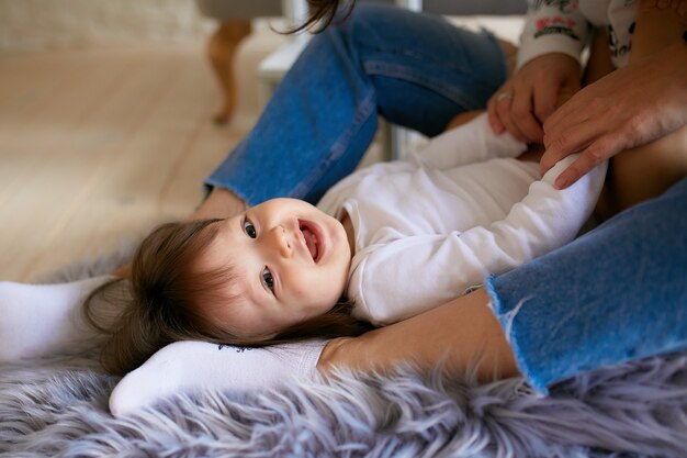 La bambina e sua madre vestita in stile casual si divertono a giocare sul pavimento