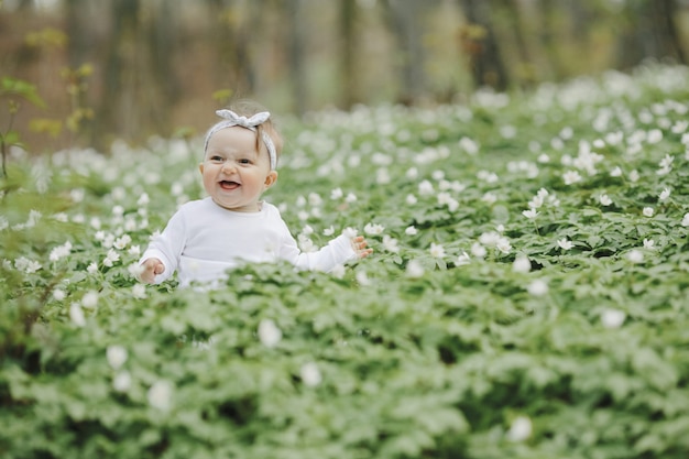 La bambina felice si siede tra i fiori nel bosco