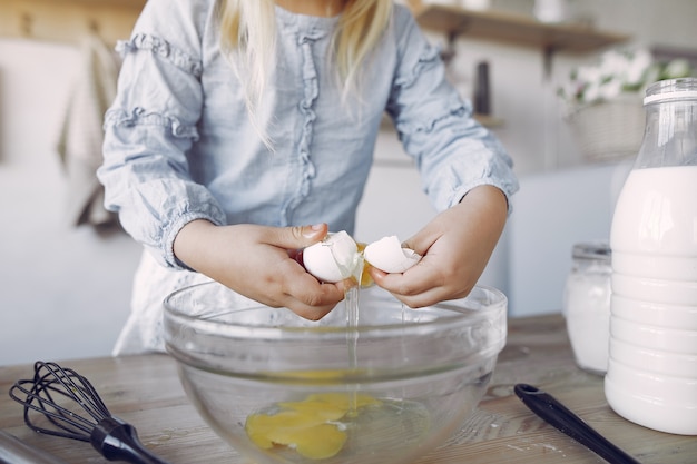 La bambina in un cappello bianco dello shef cucina l'impasto per i biscotti