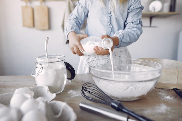 La bambina in un cappello bianco dello shef cucina l'impasto per i biscotti