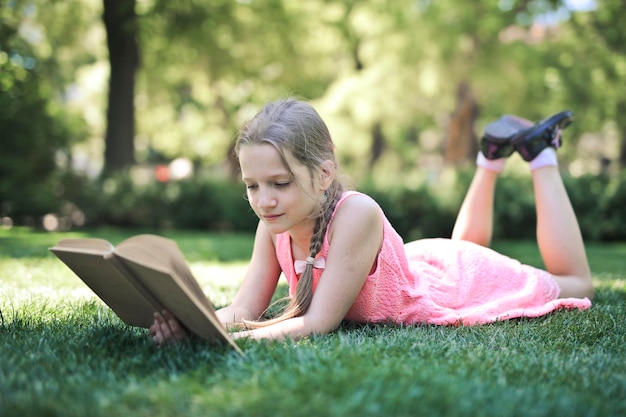 la bambina in un parco legge un libro