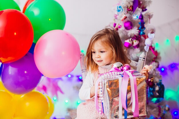 La bambina in vestito rosa gioca nella stanza con l&#39;albero di Natale rosa