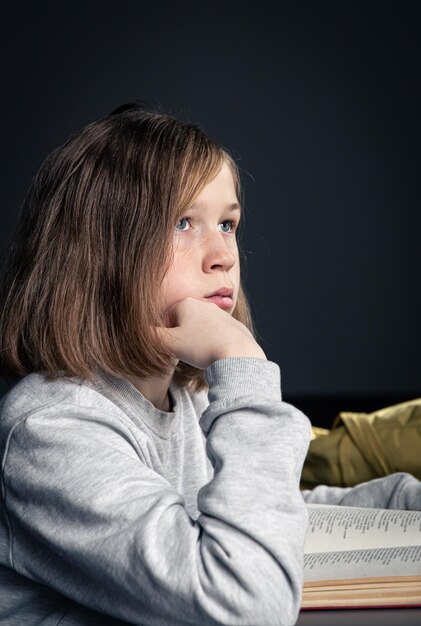 La bambina seria che legge un libro ha offuscato lo sfondo