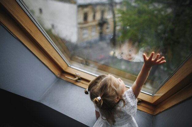 La bambina sta guardando fuori dalla finestra