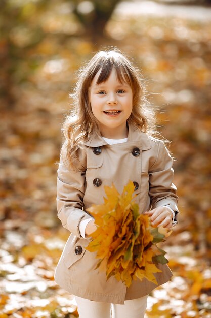 La bambina sveglia cammina in un parco di autunno con un cane