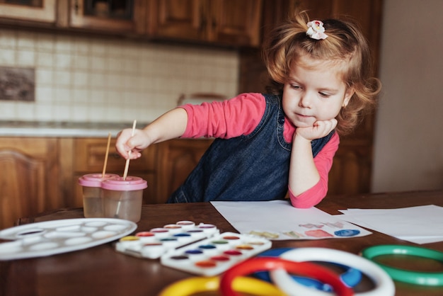 La bambina sveglia disegna un cerchio di vernici colorate