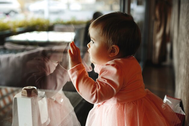 La bambina sveglia mette le sue mani sulla finestra