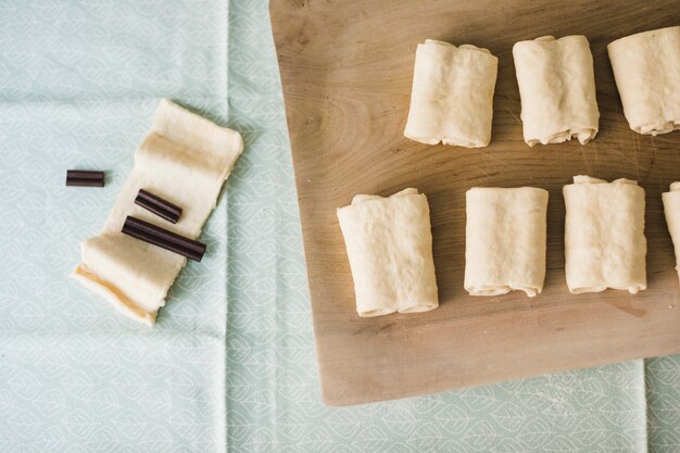 La barretta di cioccolato nella pasta sfoglia cruda piegata ha sistemato sul tagliere di legno