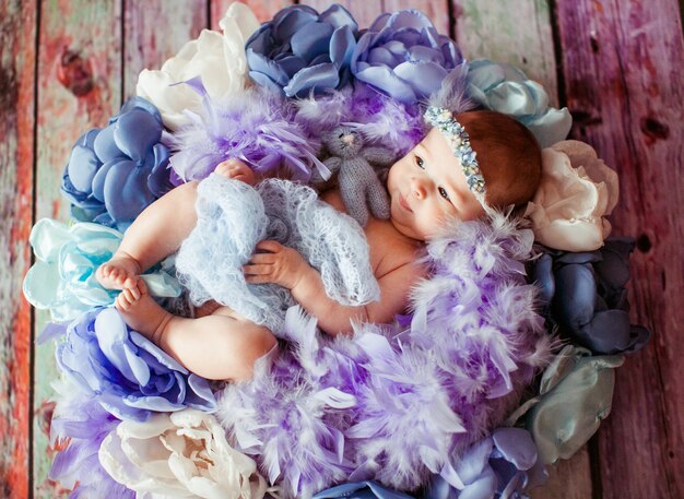 La bella bambina si trova tra vestiti viola, blu e rosa