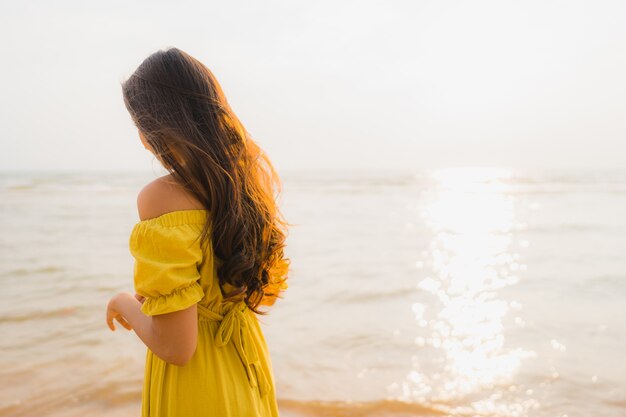 La bella camminata asiatica della giovane donna del ritratto sull&#39;oceano del mare e della spiaggia con il sorriso felice si distende