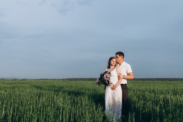 La bella coppia innamorata che abbraccia e mantiene il bouquet