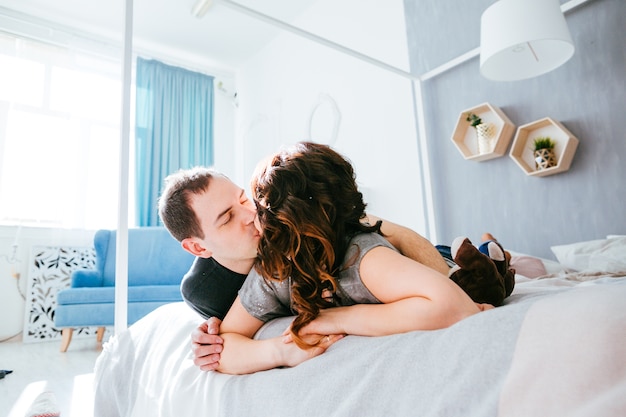 La bella coppia innamorata che si bacia sul letto