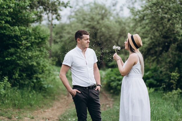 La bella coppia innamorata in piedi sull&#39;erba e soffia dandelions