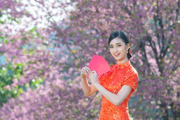 La bella donna asiatica mostra qualcosa e prende le buste rosse nel nuovo anno cinese chinese