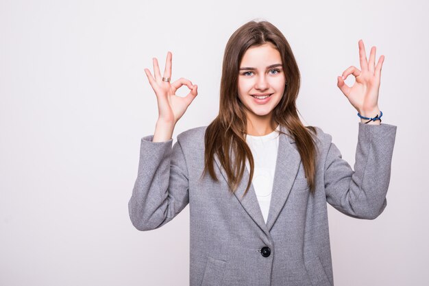 La bella donna che gesturing un lavoro eccellente firma sopra il fondo bianco